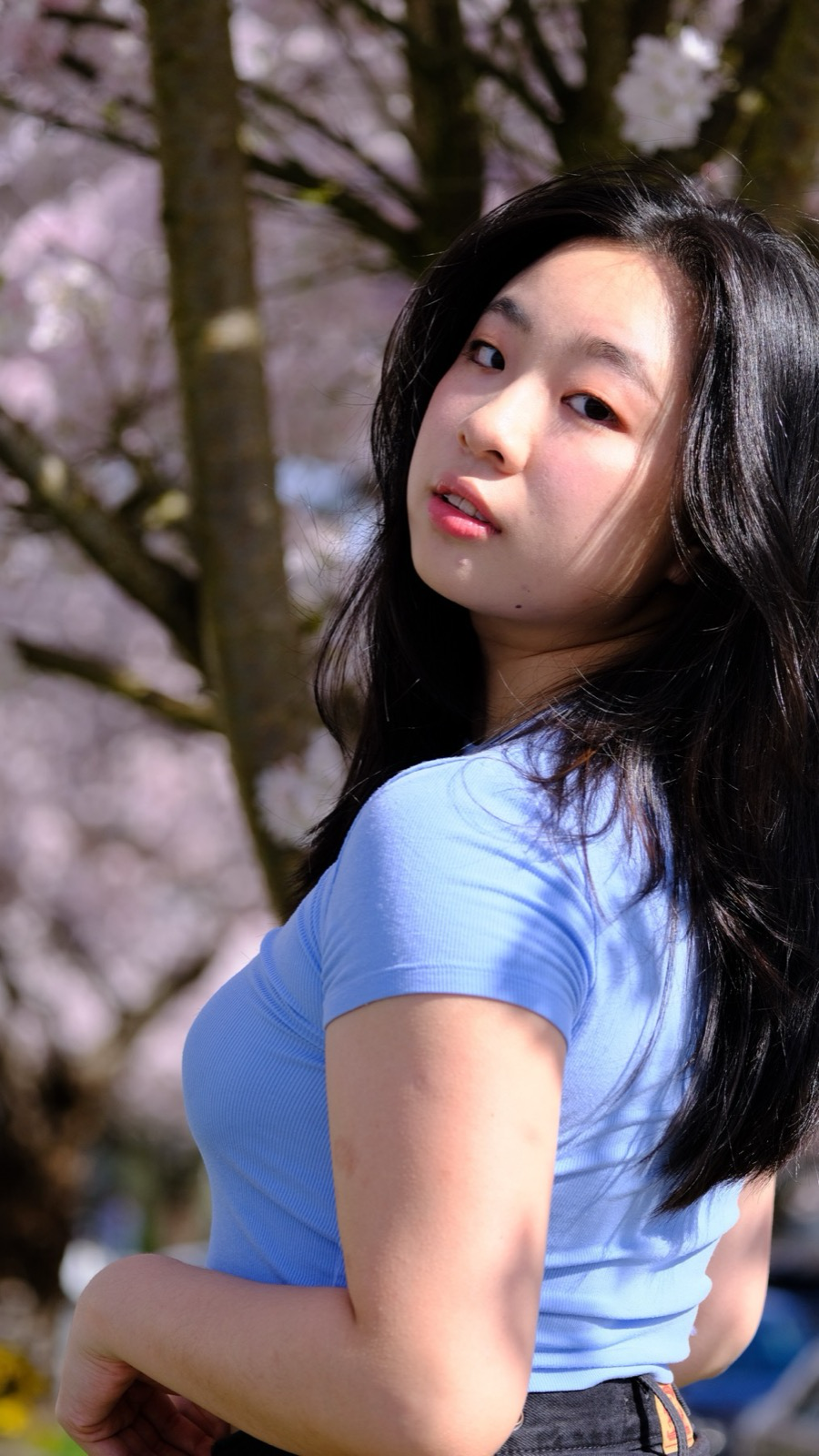 Portrait of Winnie Ma turning back beneath cherry blossoms